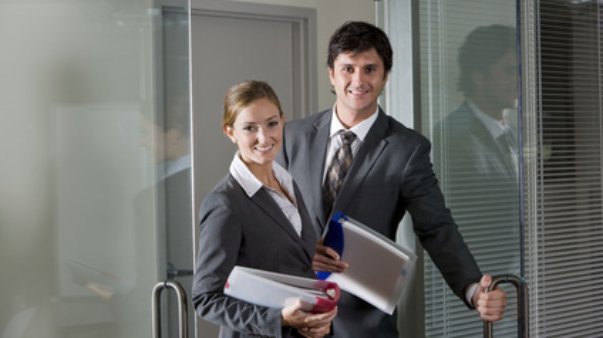 Two office workers in suits opening boardroom door